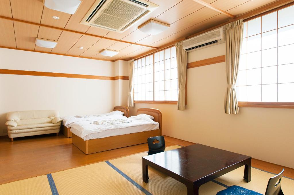 une chambre avec deux lits et une table dans l'établissement Watarase Onsen Hotel Yamayuri, à Hongu