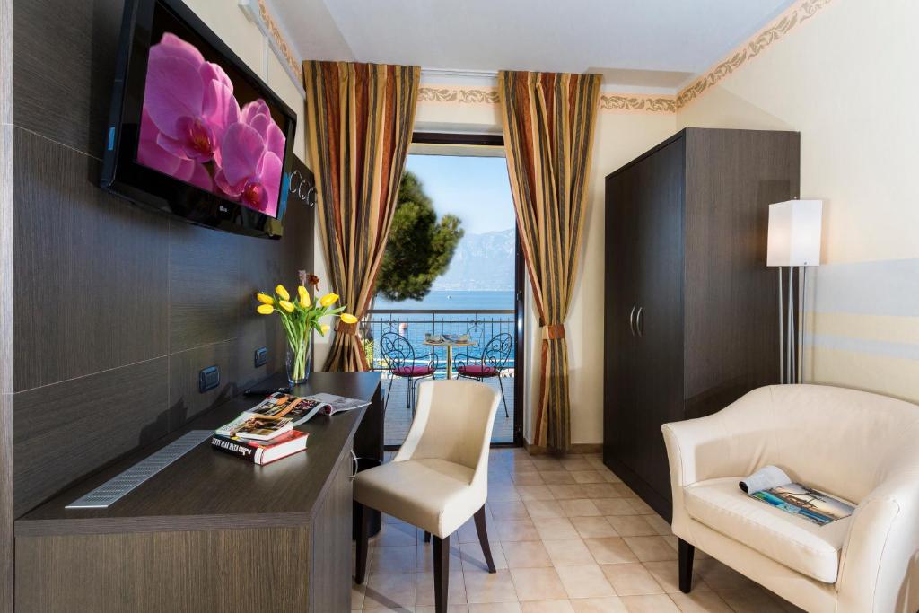 une chambre d'hôtel avec un bureau, des chaises et une télévision dans l'établissement Taki Village, à Brenzone