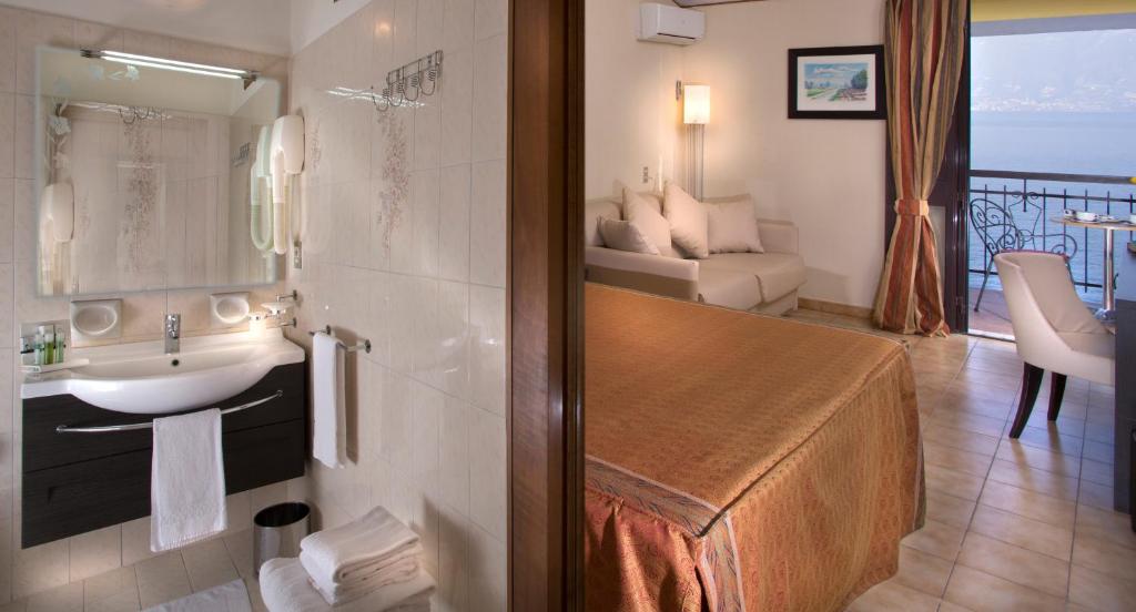 une salle de bain avec lavabo et un salon dans l'établissement Taki Village, à Brenzone