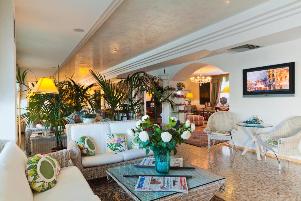 - un salon avec des canapés et une table avec des fleurs dans l'établissement Hotel Panoramic, à Caorle