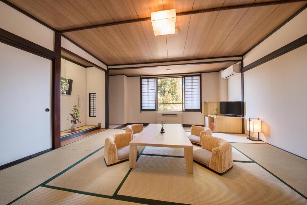 un salon avec une table, des chaises et une télévision dans l'établissement Oribana, à Omachi