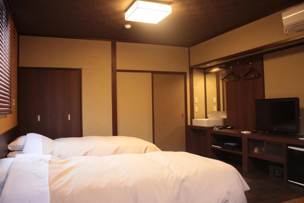 une chambre d'hôtel avec deux lits et une télévision à écran plat dans l'établissement Tokiwa Ryokan, à Nikkō