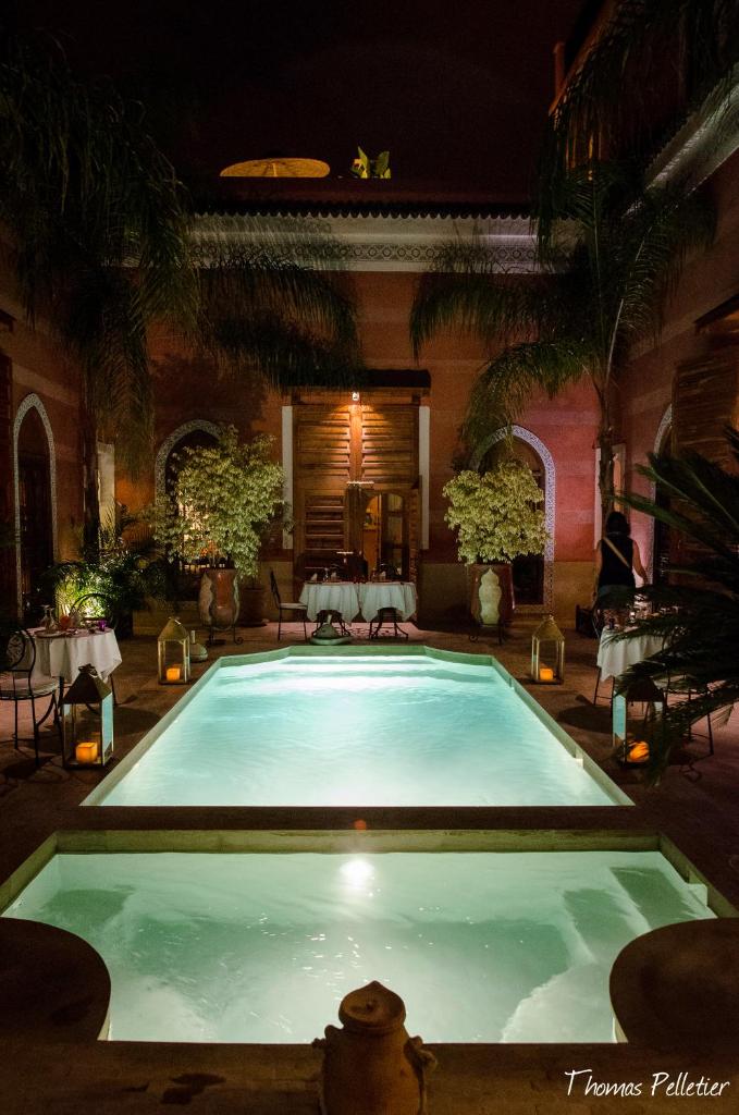 - une grande piscine dans une cour la nuit dans l'établissement Riad Alili, à Marrakech
