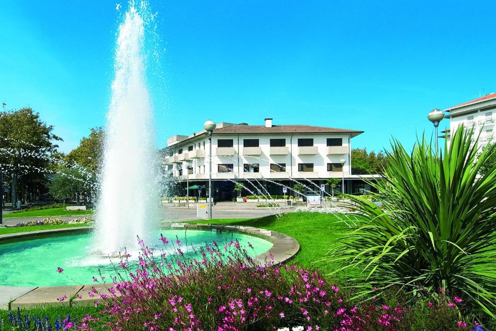 une fontaine dans un parc avec un bâtiment en arrière-plan dans l'établissement Hotel Genzianella, à Cervia