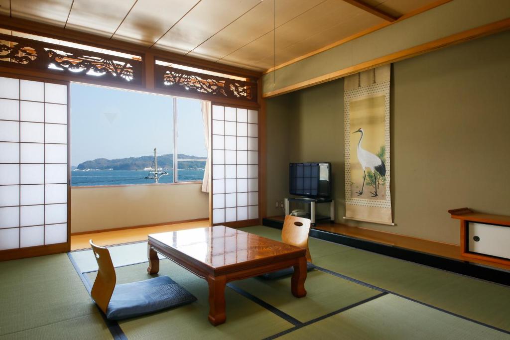 un salon avec une table et une grande fenêtre dans l'établissement Bekkan Yosanoso, à Miyazu