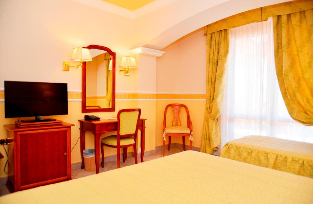 une chambre d'hôtel avec un lit, un bureau et une télévision dans l'établissement Afrodite Boutique Hotel, à Bovalino Marina