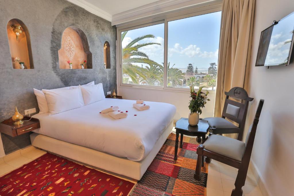 une chambre avec un lit, une fenêtre et une chaise dans l'établissement Riad Diamant Blanc, à Essaouira