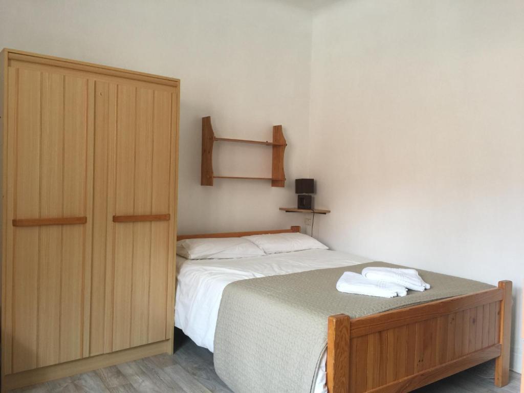 une chambre avec un lit et une armoire en bois dans l'établissement Résidence Natura, à Ax-les-Thermes