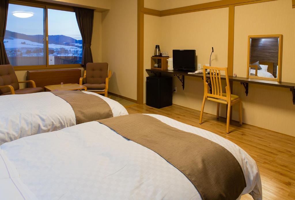 Cette chambre comprend deux lits et un bureau avec un ordinateur. dans l'établissement Oehonke, à Kitami