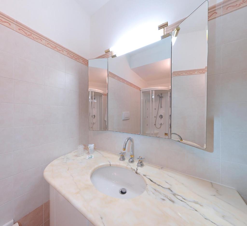 La salle de bains est pourvue d'un lavabo en marbre et d'un miroir. dans l'établissement Hotel Le Cave, à Sirolo