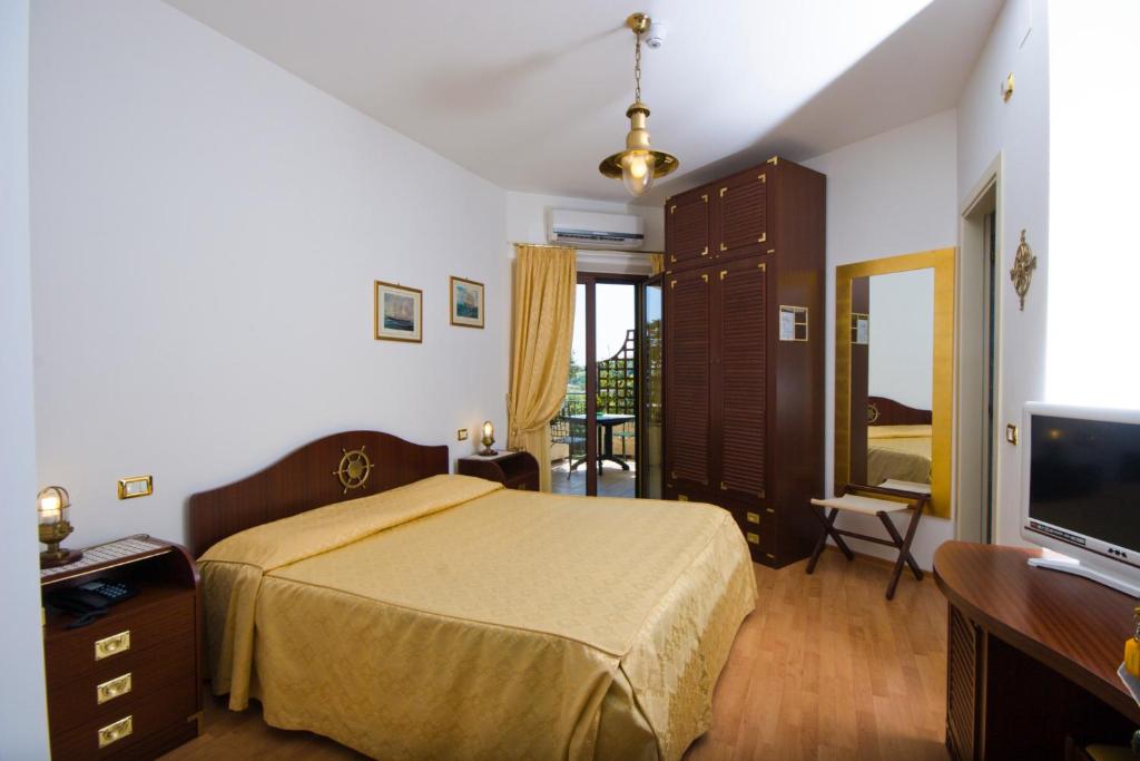 une chambre avec un lit, un bureau et une télévision dans l'établissement Hotel Le Cave, à Sirolo