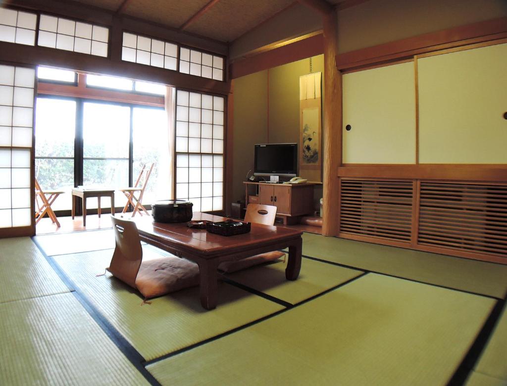 - un salon avec une table dans une pièce dotée de fenêtres dans l'établissement Nishiki Onsen Kurion, à Senboku
