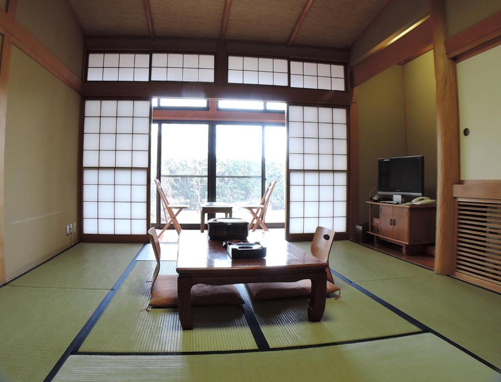 un salon avec une table, des chaises et des fenêtres dans l'établissement Nishiki Onsen Kurion, à Senboku 7 autres photos