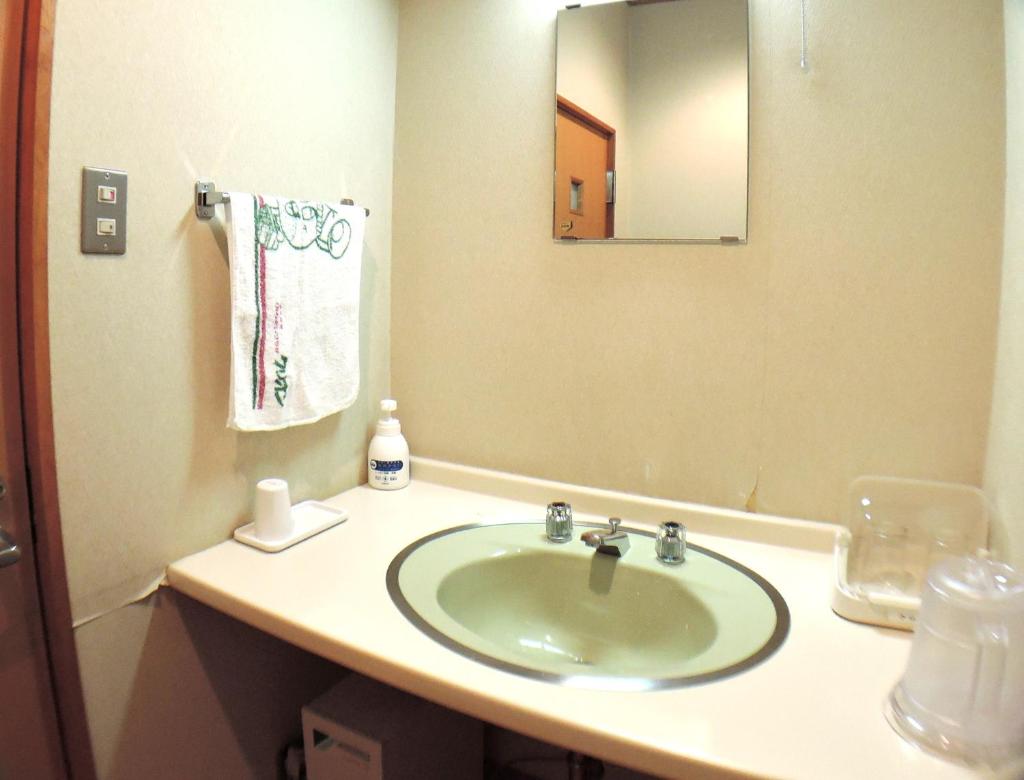 une salle de bain avec un lavabo et un miroir dans l'établissement Nishiki Onsen Kurion, à Senboku
