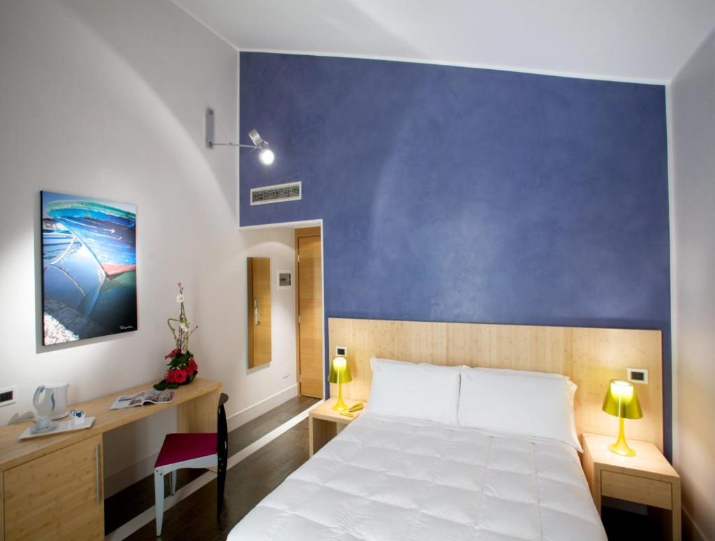 une chambre avec un lit blanc et un mur bleu dans l'établissement Hotel Intervallo, à Torre Lapillo