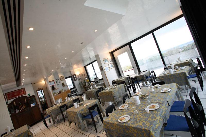 une salle à manger avec tables, chaises et fenêtres dans l'établissement Hotel Intervallo, à Torre Lapillo