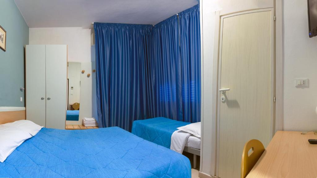 - une chambre avec des rideaux bleus, un lit et une table dans l'établissement Hotel Savina, à Rimini