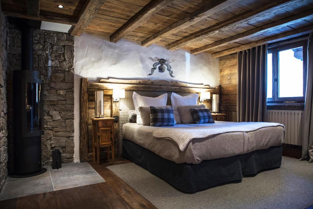une chambre avec un grand lit dans un mur de pierre dans l'établissement La Bouitte - Hôtel Relais & Châteaux, à Saint-Martin-de-Belleville
