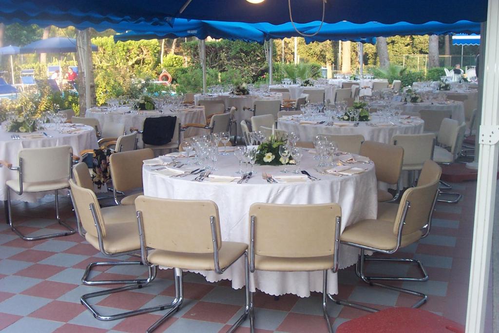 un ensemble de tables et de chaises avec des nappes blanches dans l'établissement Grand Hotel Golf, à Tirrenia