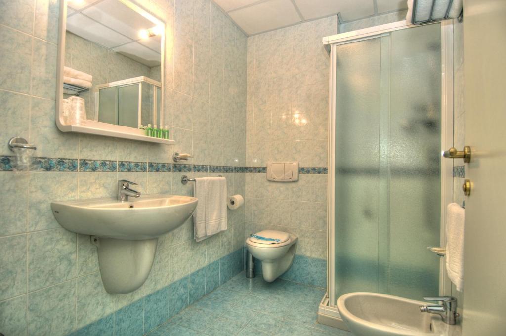 une salle de bain avec un lavabo, des toilettes et une douche dans l'établissement Hotel Minerva, à Lignano Sabbiadoro