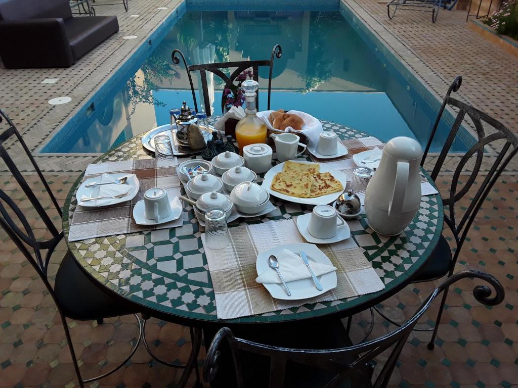 - une table avec de la nourriture pour le petit-déjeuner à côté de la piscine dans l'établissement Riad Anma, à Taroudant