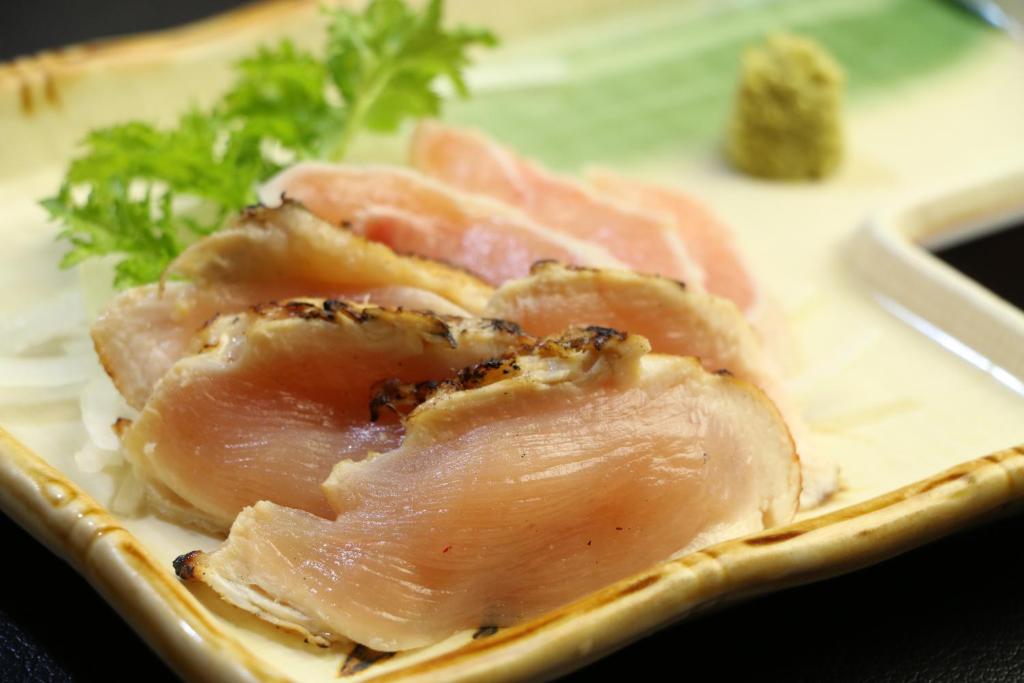 deux morceaux de viande sur une plaque à feuilles vertes dans l'établissement Minshuku Shiroyama, à Taketa
