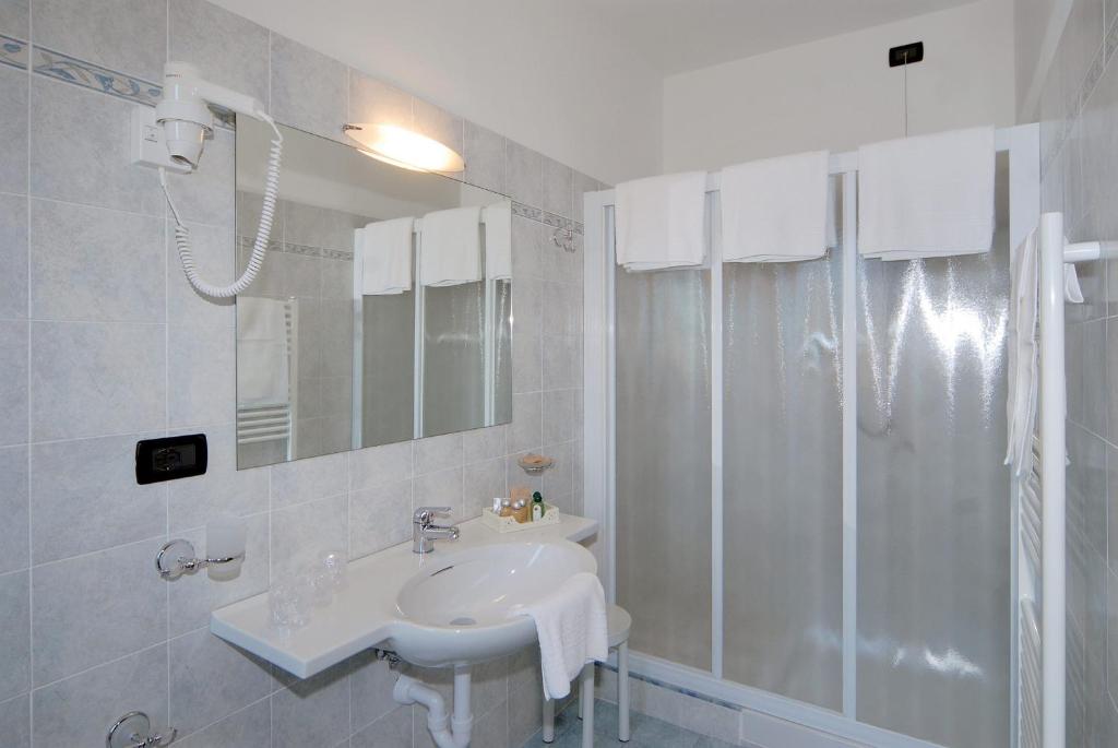 une salle de bain blanche avec lavabo et douche dans l'établissement Piccolo Hotel, à Diano Marina