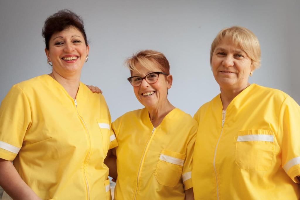 Trois femmes en chemises jaunes posant une photo dans l'établissement Residence La Palma, à Marina dʼAndora