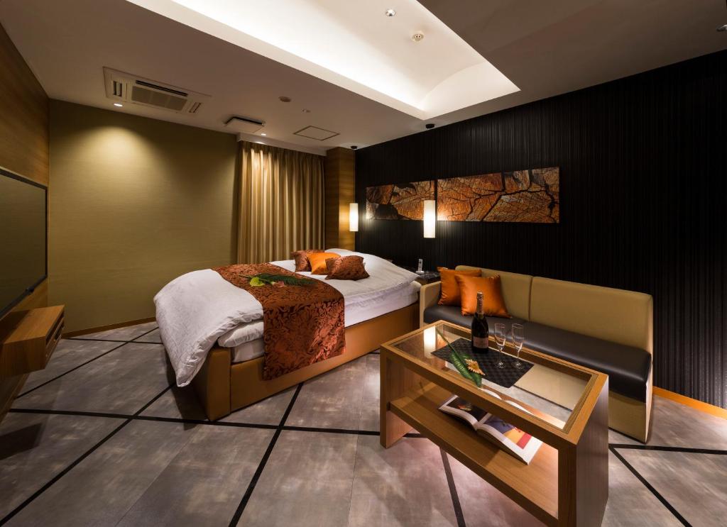 une chambre d'hôtel avec un lit et un canapé dans l'établissement Hotel Plant Garden Resort (Adult Only), à Toyokawa