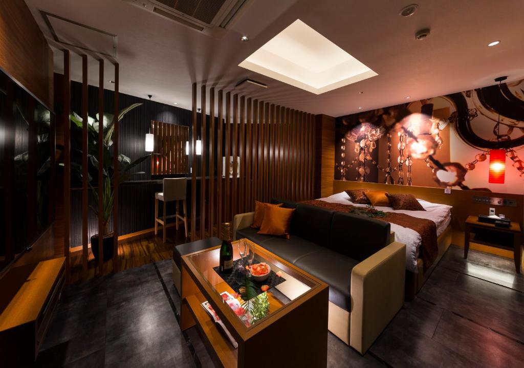 un salon avec un canapé et un lit dans l'établissement Hotel Plant Garden Resort (Adult Only), à Toyokawa