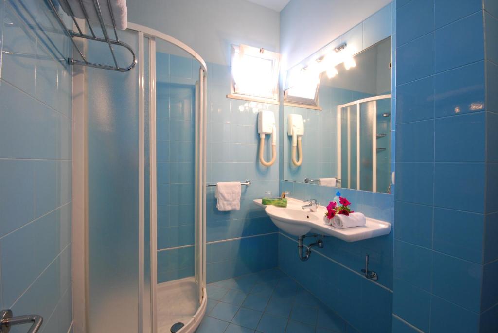 une salle de bain bleue avec un lavabo et une douche dans l'établissement Hotel Costa Verde, à Tortoreto Lido