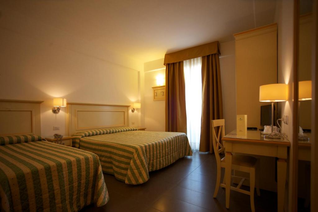 une chambre d'hôtel avec deux lits et un bureau dans l'établissement Hotel Stella Marina, à San Vincenzo