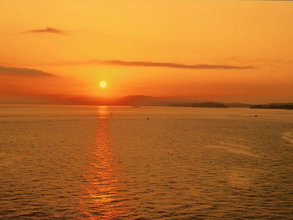 un coucher de soleil sur une grande étendue d'eau dans l'établissement Hotel New Awaji, à Sumoto