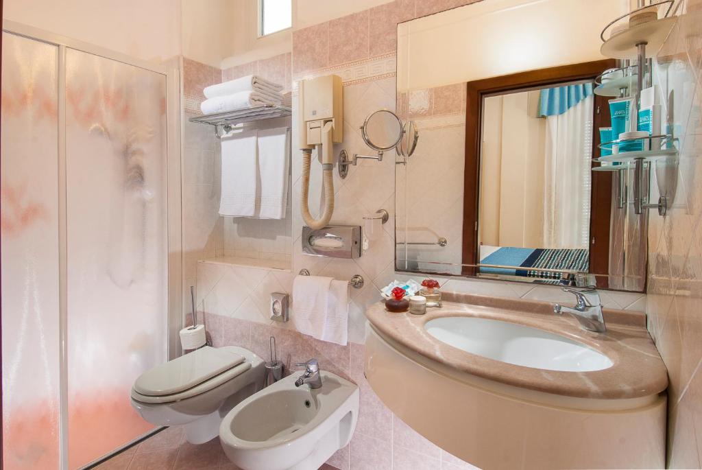 une salle de bain avec un lavabo, des toilettes et un miroir dans l'établissement Hotel Helios, à Rimini