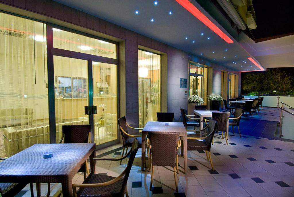 un restaurant avec des tables, des chaises et des fenêtres dans l'établissement Hotel St. Moritz, à Bellaria-Igea Marina