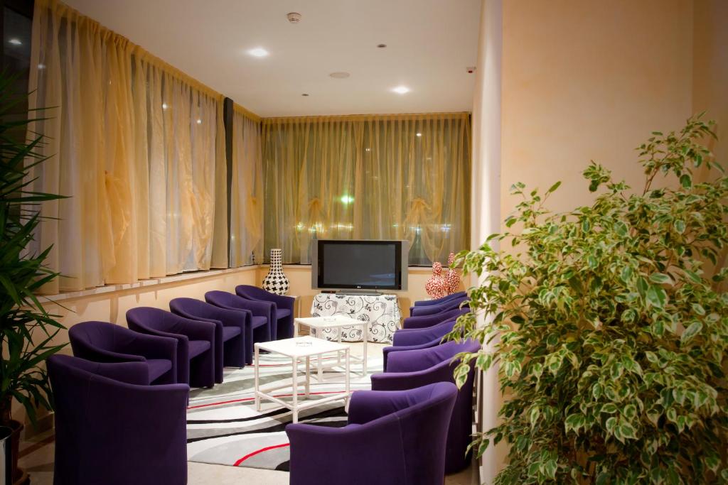 une salle de conférence avec des chaises violettes et une télévision dans l'établissement Hotel Parigi, à Caorle