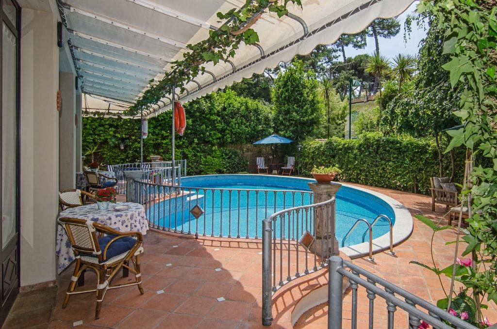 une piscine avec une table et des chaises à côté dans l'établissement Hotel Kyrton, à Forte dei Marmi