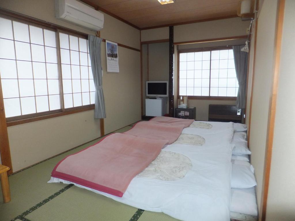 Cette chambre comprend un grand lit et 2 fenêtres. dans l'établissement Minshuku Iwatakan, à Takayama