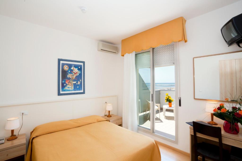 une chambre avec un lit et une fenêtre avec un balcon dans l'établissement Hotel Parigi, à Caorle