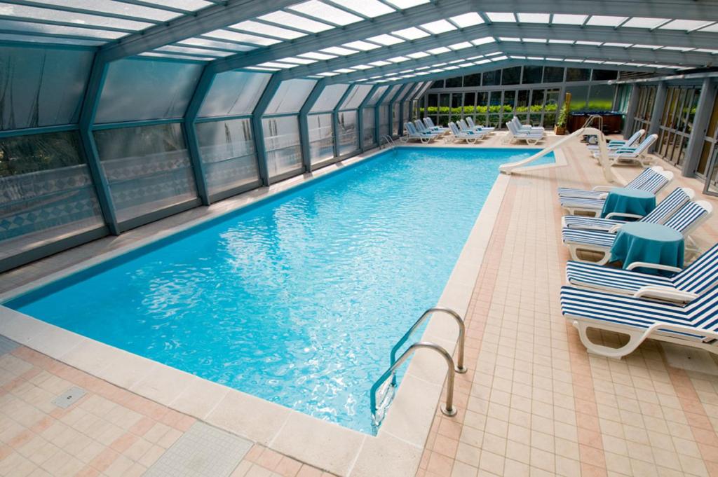 - une grande piscine avec des chaises longues dans un bâtiment dans l'établissement Hotel Ai Pini, à Grado 102 autres photos