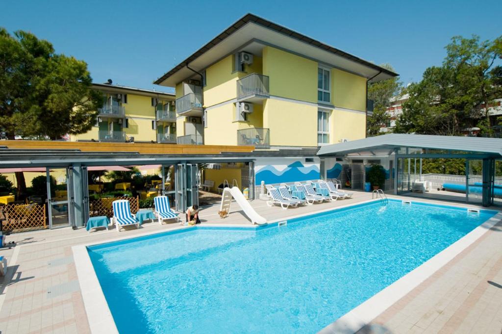 une piscine avec des chaises et un bâtiment dans l'établissement Hotel Ai Pini, à Grado