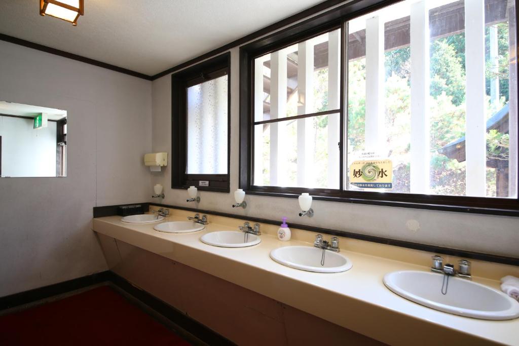 une salle de bain avec trois lavabos et deux fenêtres dans l'établissement Iwamura Sanso, à Ena