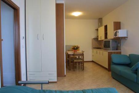 un salon avec un canapé bleu et une cuisine dans l'établissement Residence Mini Sayonara, à Lido di Jesolo 1 autre photo