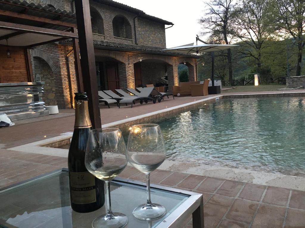 2 verres à vin assis sur une table à côté d'une piscine dans l'établissement Villa valtopina, à Valtopina