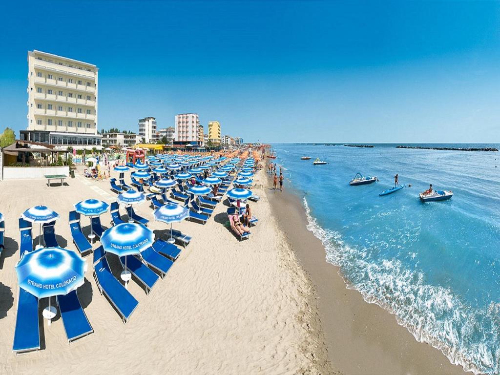 - une plage avec un bouquet de parasols bleus et blancs dans l'établissement Strand Hotel Colorado, à Lido di Savio