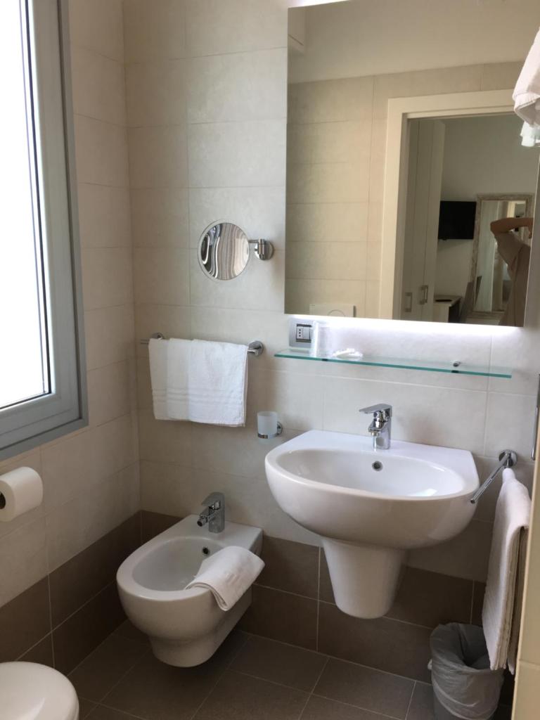 une salle de bain blanche avec un lavabo et des toilettes dans l'établissement Hotel Novella, à Misano Adriatico 17 autres photos