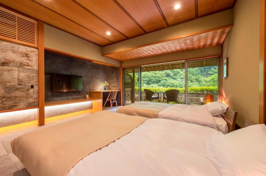 deux lits dans une chambre avec une fenêtre dans l'établissement Fujiiso, à Takayama