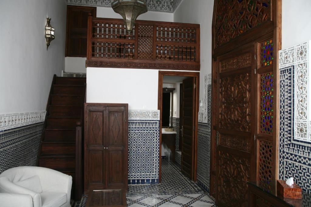 Cette chambre dispose de portes en bois et d'une chaise blanche. dans l'établissement Riad Batchisarai, à Fès