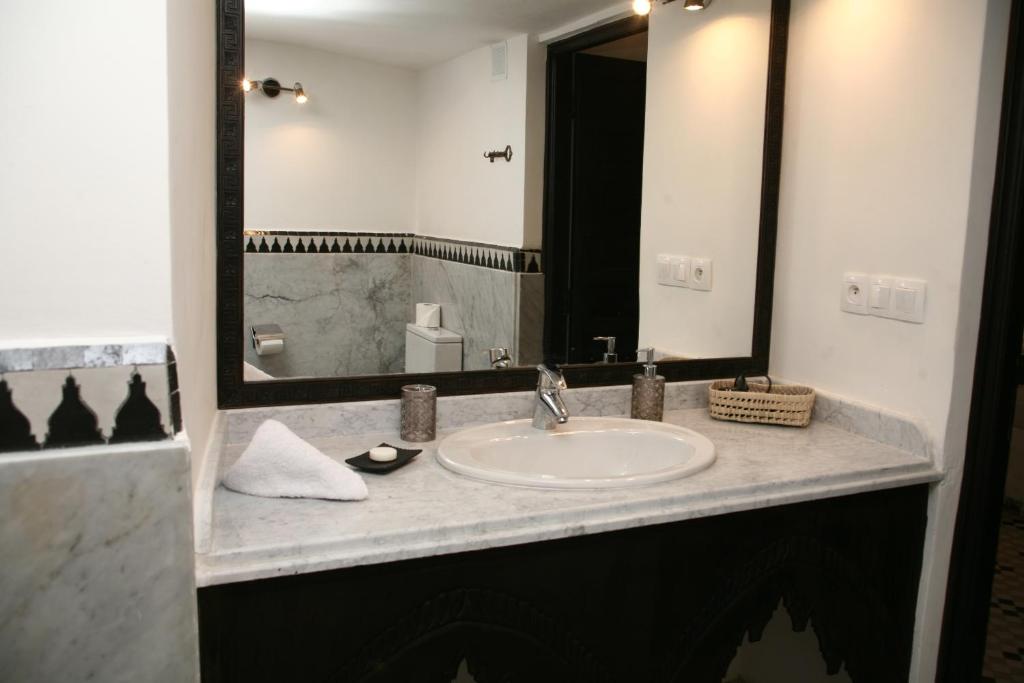 une salle de bain avec un lavabo et un grand miroir dans l'établissement Riad Batchisarai, à Fès