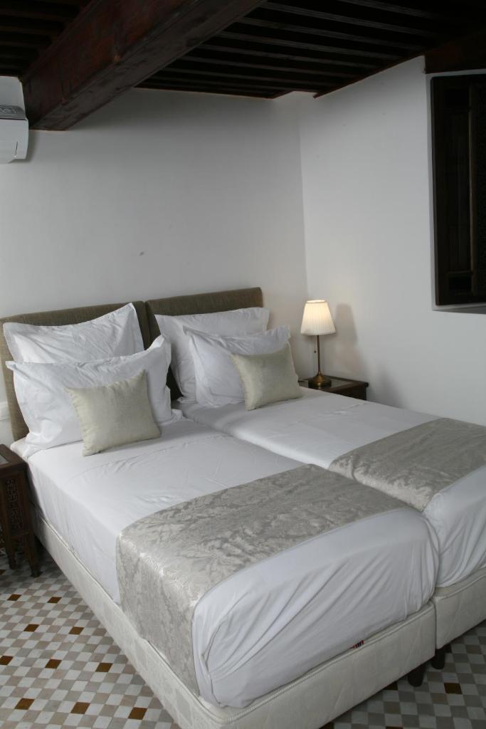 Elle comprend un grand lit avec des draps et des oreillers blancs. dans l'établissement Riad Batchisarai, à Fès